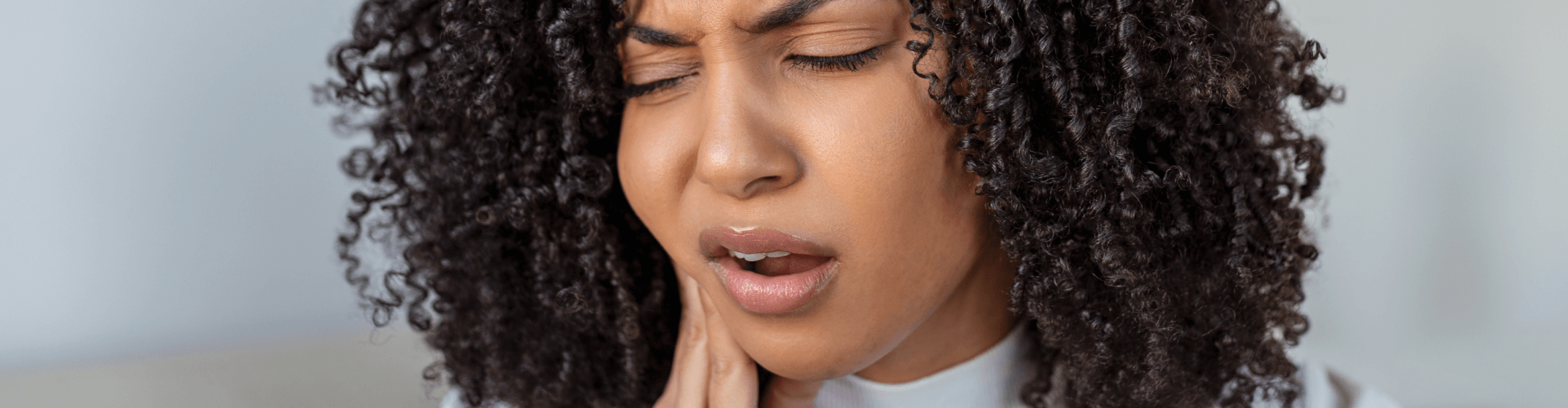 Woman holding her cheek in pain.